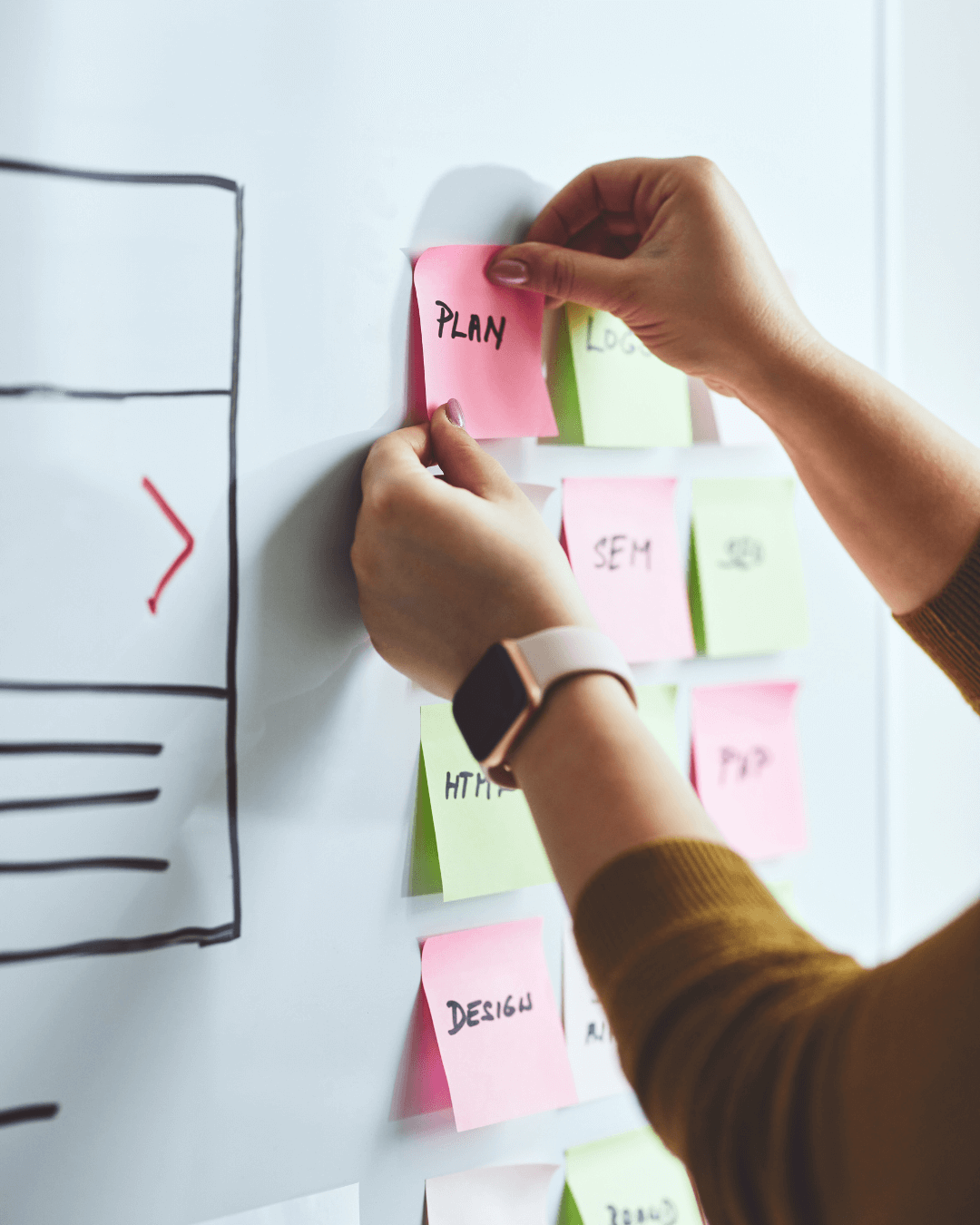 Hände kleben bunte Notizzettel mit Begriffen wie Plan und SEM an ein Whiteboard – Webdesign-Strategie-Workshop in Villingen-Schwenningen